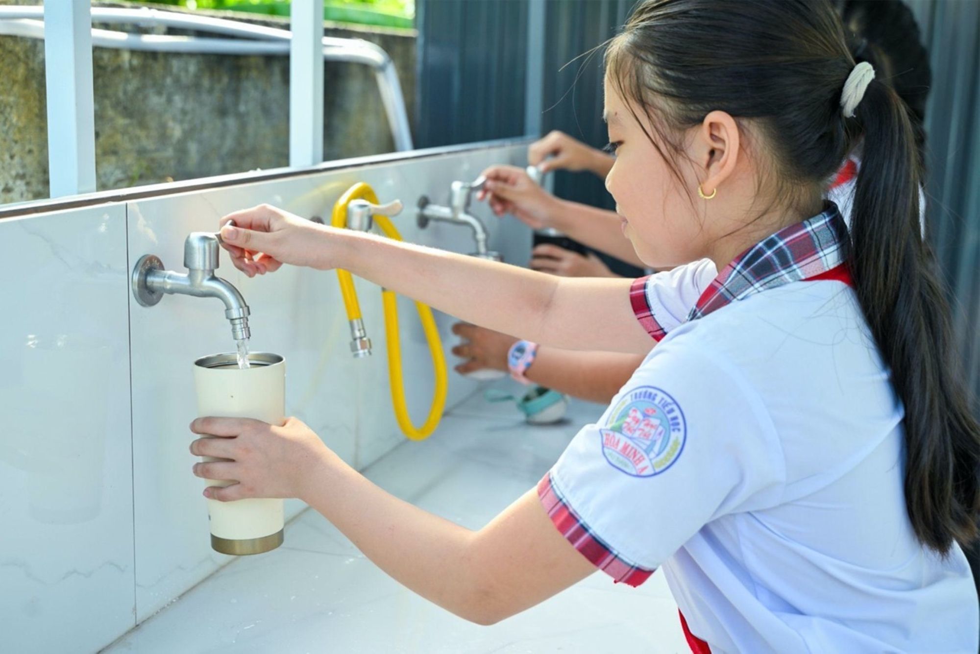 Các em học sinh trực tiếp sử dụng nước từ hệ thống thu trữ, lọc nước uống do UNIQLO tài trợ